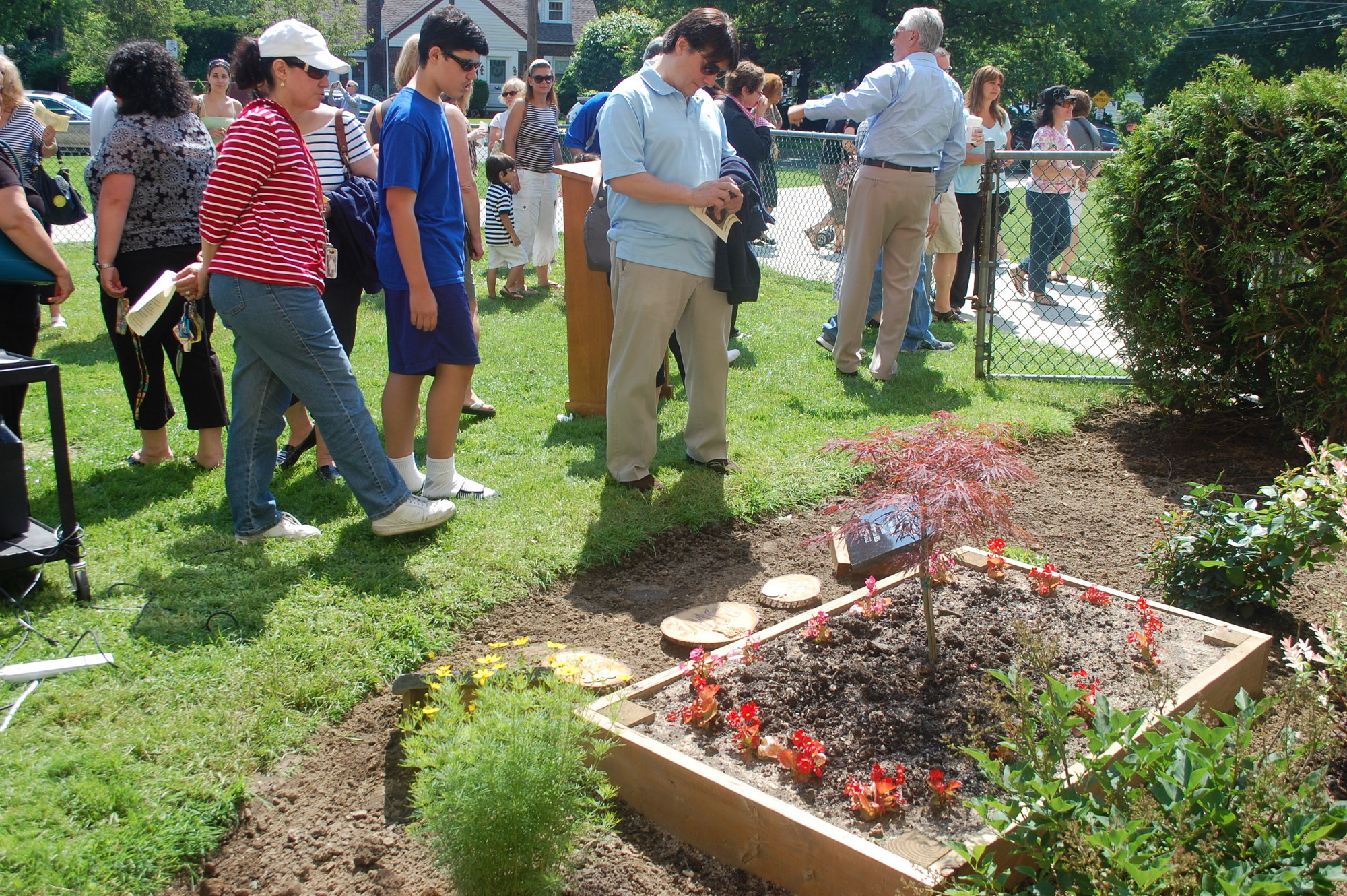 Guests at last Saturday morning’s ceremony look over the garden built outside of Memorial Junior High School in honor of former teacher Stephanie Ginsberg.