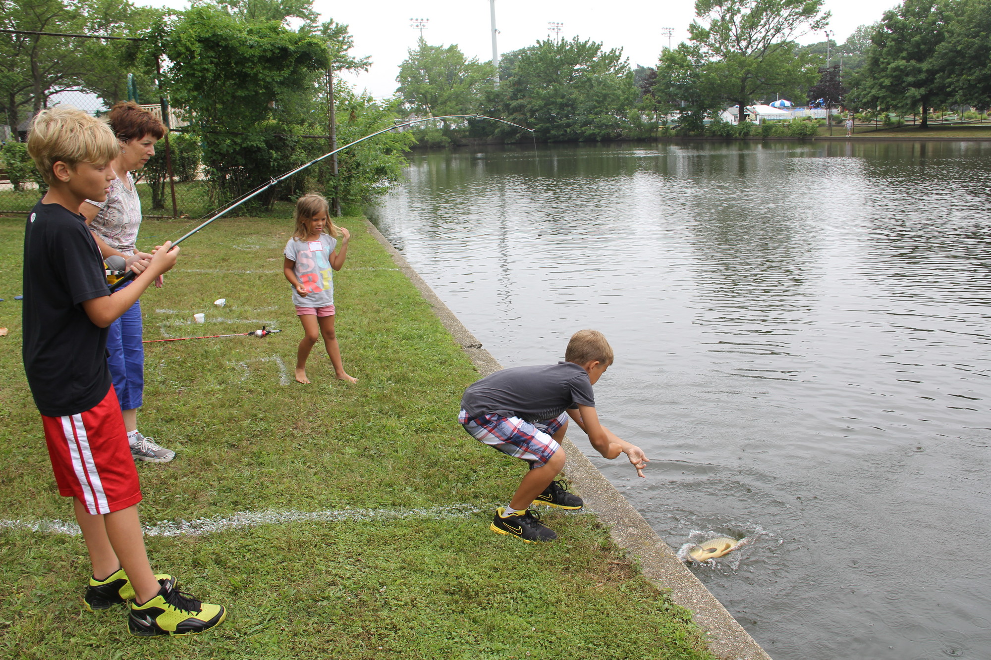Jesper Dalessandro, 11, reeled in a large bass while his brother Tyler, 9, helped pull it from the water, as their grandmother, Sue, and sister, Molly, 7, watched.