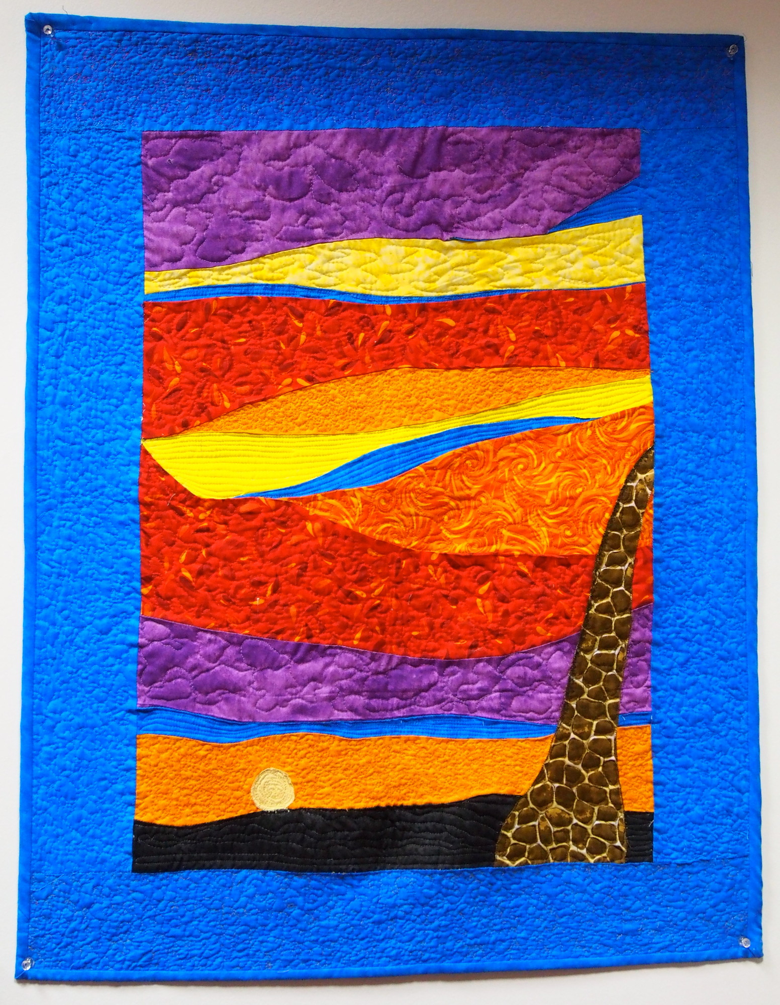 This quilt, Sunset on the Serengeti, was inspired by a conversation with the artist’s daughter. The discussion was about clashing colors and how hues that don’t complement one another in fashion often do so in nature.