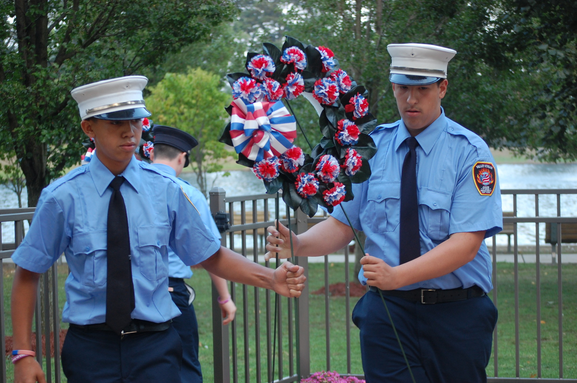 Junior firefighters, including Mike Irizarry, left, and Capt. Richie Field, placed memorial wreaths at the monument in Hendrickson Park.