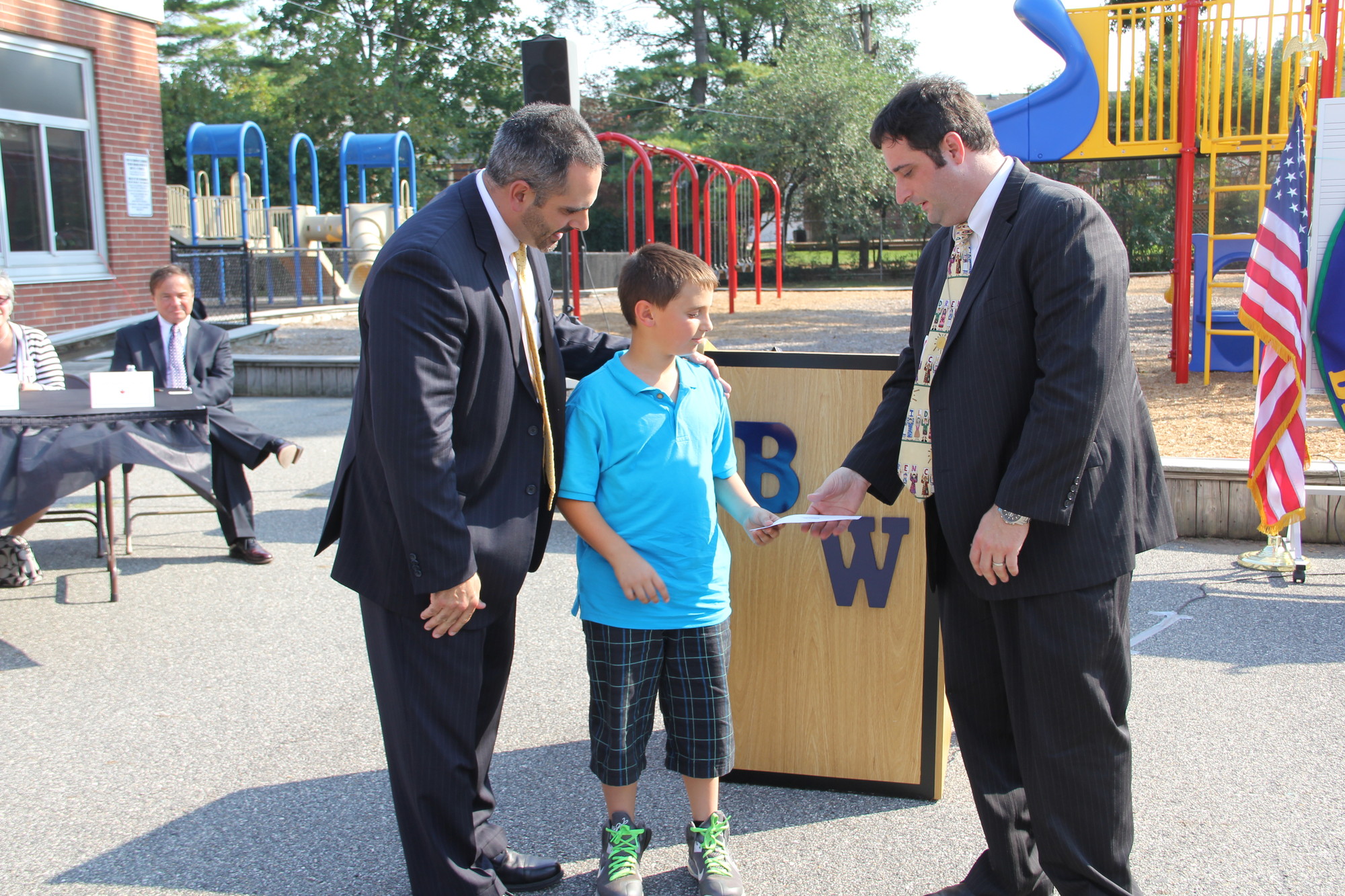 Barnum Woods fourth-grader Nicholas Goldstein and Principal Gregory Bottari, left, presented Francis X. Hegarty Principal Jacob Russum with an $18,500 donation last Friday.