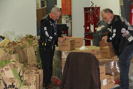 Mark “Fuzzy” Weiss, vice president of the IDONTKNOW Motorcycle Club, and Bobby Beard help unpack boxes of non-perishible food items that will be portioned out with other goods to be given to less fortunate families.