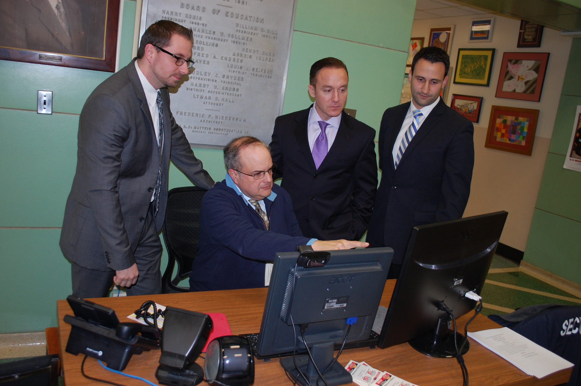 John Venza, one of District 24’s security guards, looked over the new monitoring system at the William L. Buck School with principals, standing from left, Mark Onorato, Dr. Scott Comis and Rosario Iacono, before the Dec. 12 board meeting.