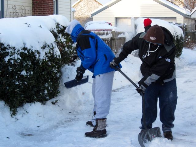 From left, bundled-up residents Pace Shaw and Keith Pfifer shoveled out a home on Madison Avenue, with help from Jordan Smith, rear.