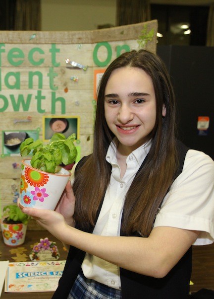 Malverne resident Alexis DePaola is smiling as she exhibits her project on how different types of soil effects plant growth.