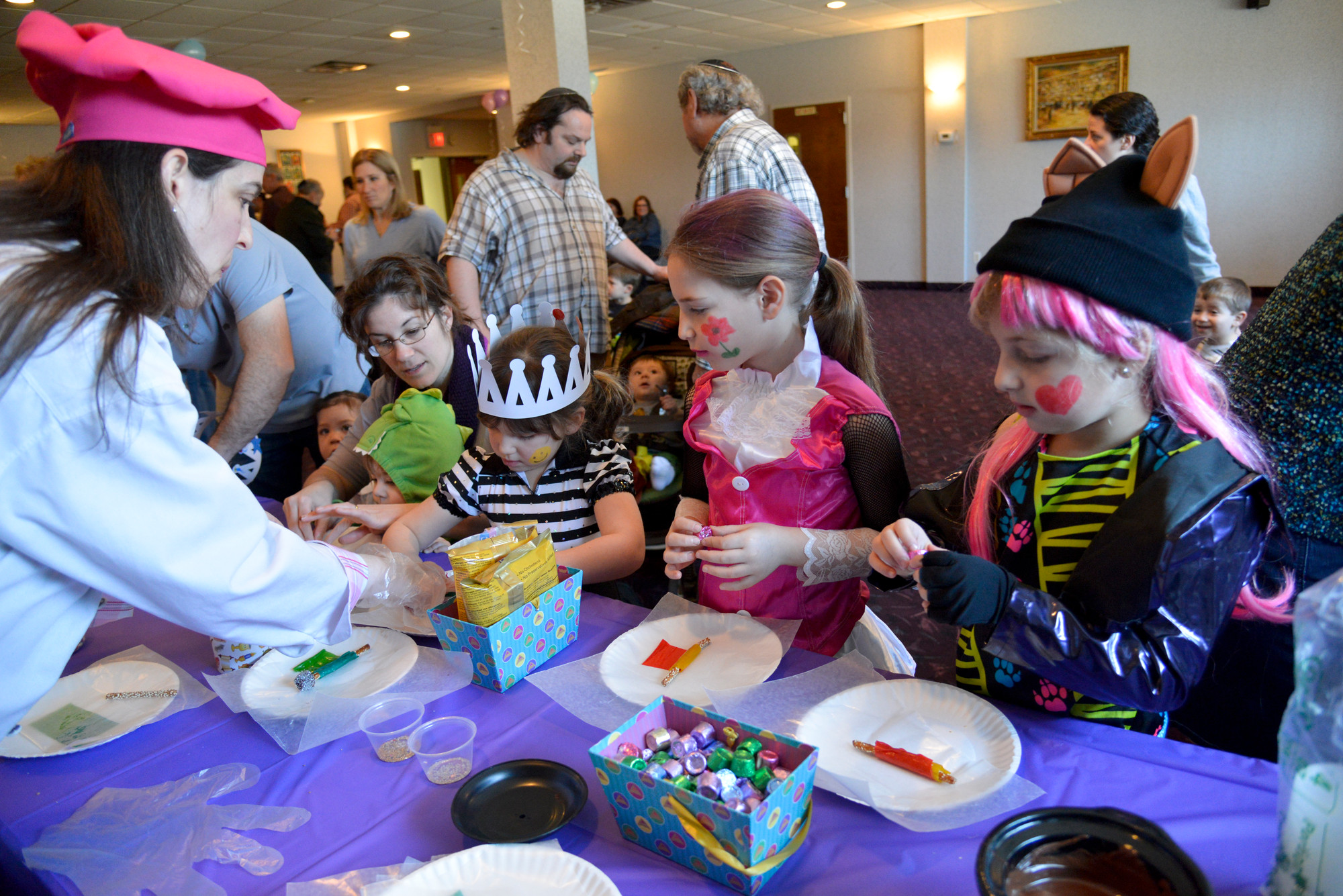 Paula Gottlieb Herman, left, created edible crafts with Chelsey Fenster, 4, center, Sarah Lazerson, 6, and Alexandra Fenster 6, at the East Meadow Jewish Center’s third annual Purim With a Purpose children’s event. The fundraiser netted $3,300 which will be dispersed to two children’s charities.