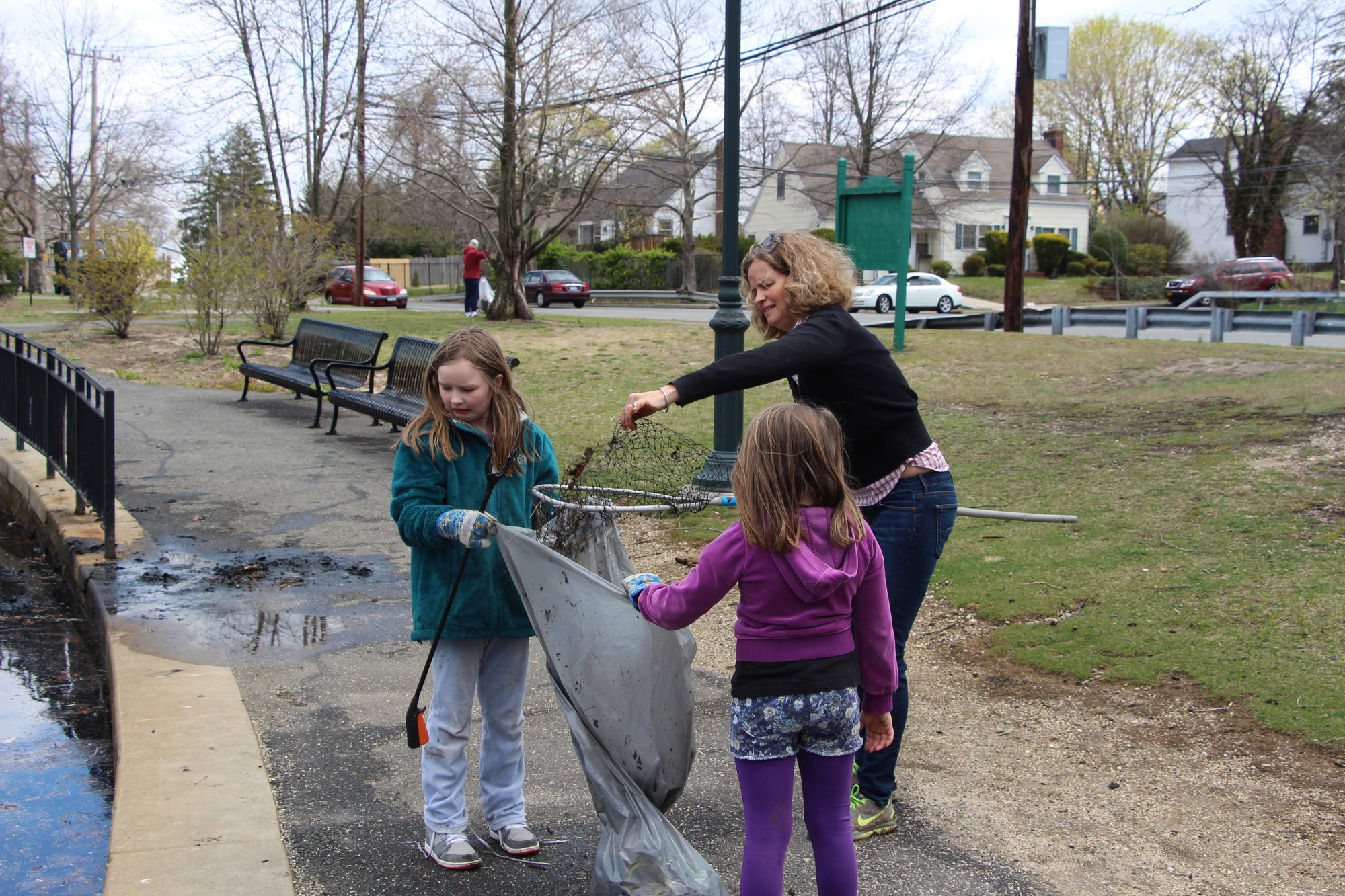 Nassau County Leg. Laura Curran, with her daughters Molly, right, and Julie, helped scoop out some debris from the Silver Lake.