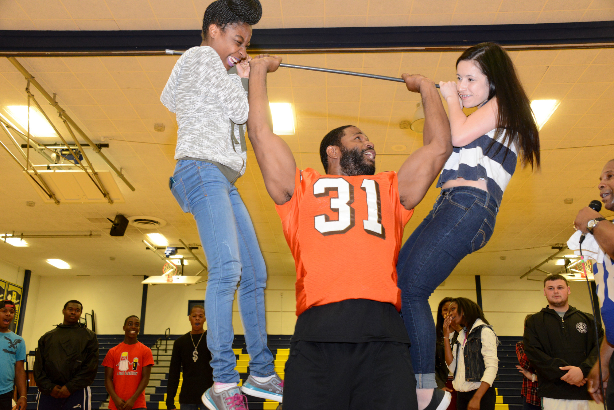 Former Cleveland Browns running back Willie Green lifted Olivia Asuncion, left, and Amelia Jean during a Winners Inc. assembly at Baldwin High School on May 15.