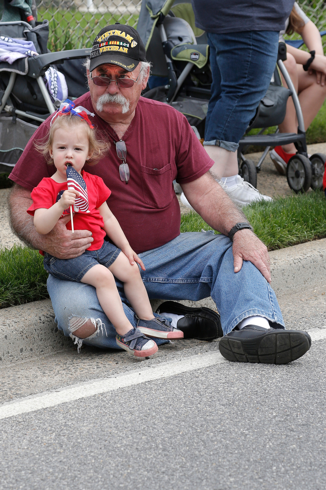 Vietnam veteran John Ochtera and his 16-month old granddaughter Lauren watch the procession from their curbside spot on Prospect Avenue.