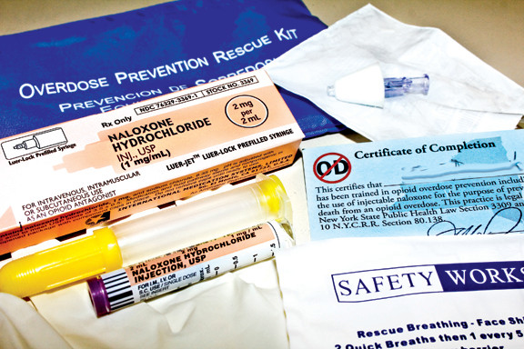 An overdose prevention kit, distributed at a Nassau County Narcan training session, comprises two latex gloves, a face shield for rescue breathing, a nasal syringe, a pre-filled vial of Naloxone and a certificate of completion.