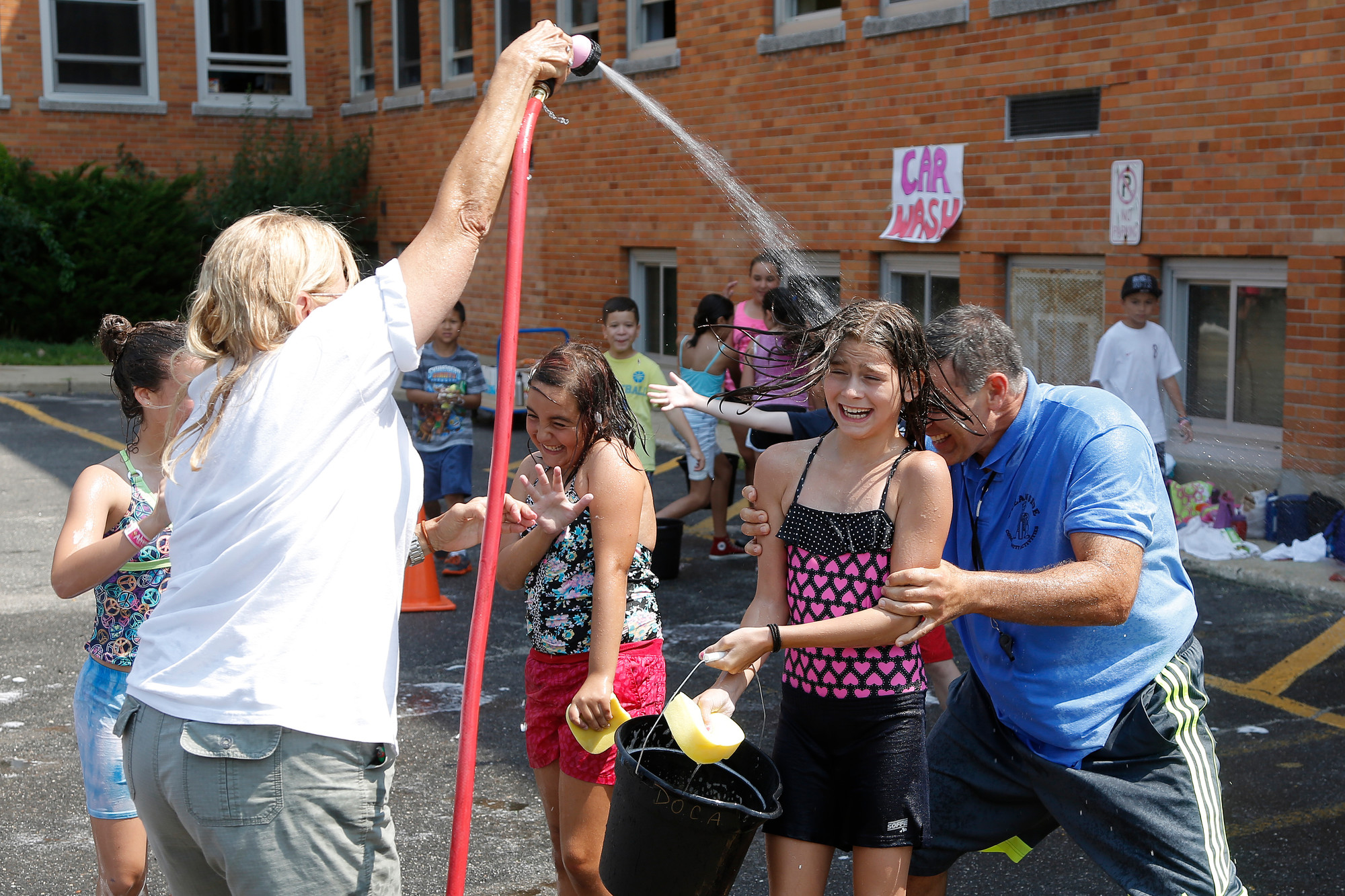 Extended Playground Camp head counselor Chris Marzo tried to avoid being soaked by camp supervisor, Nancy Baxter, as he hid behind 6th grader Eve Scarola at the camp’s fundraiser car wash.
