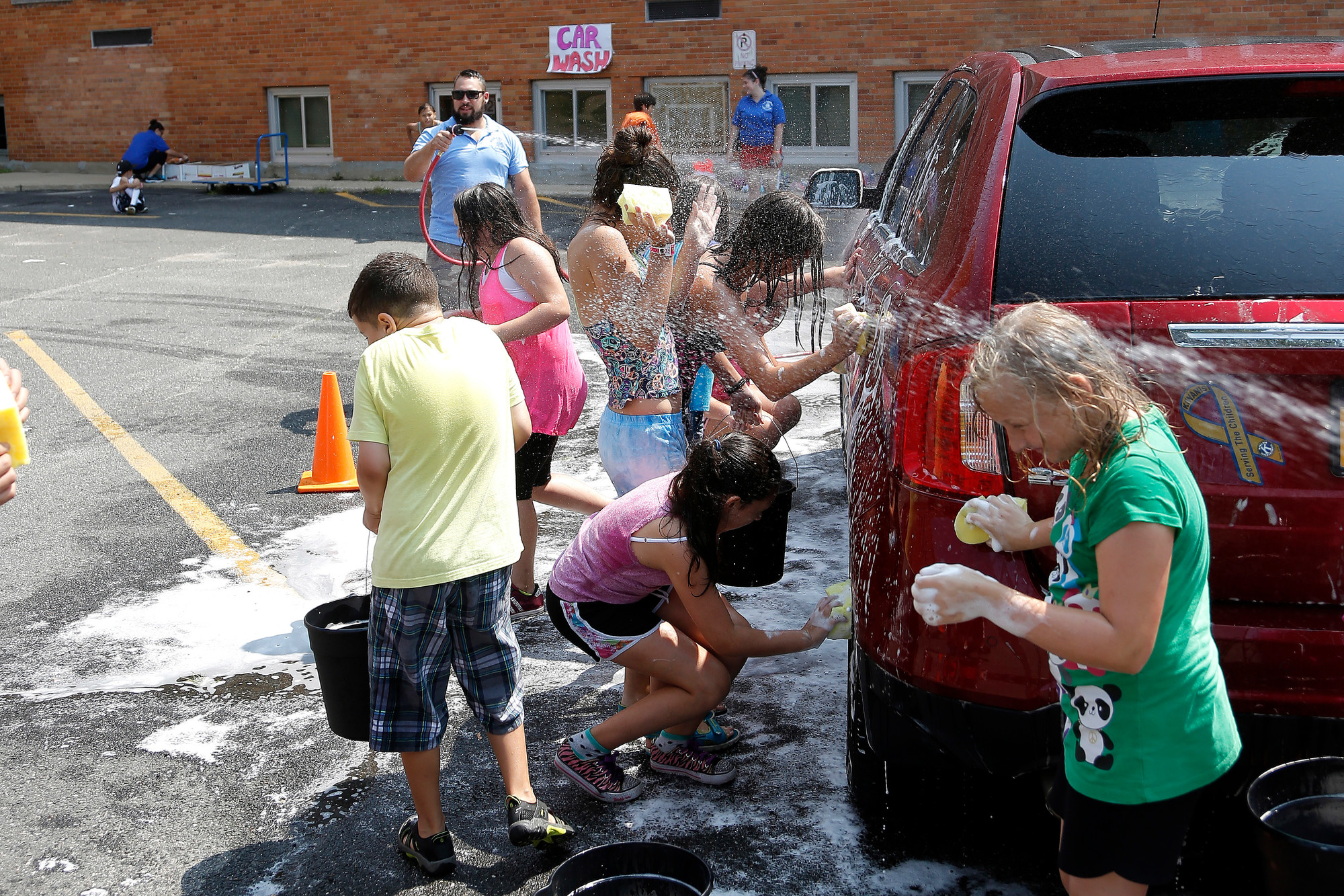 Volunteers from the Extended Playground Camp, along with the car they are washing, entered the rinse cycle.