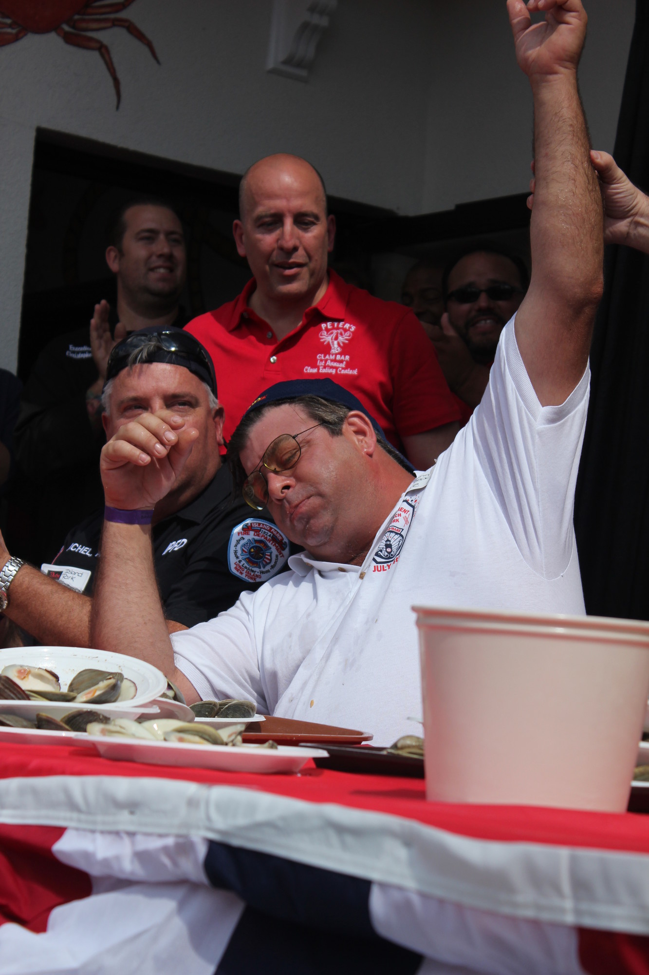 Long Beach firefighter Richie Santoro raised his hand in victory after eating eight dozen clams and earning a $2500 prize for his station in the Peter’s Clam Bar eating contest.