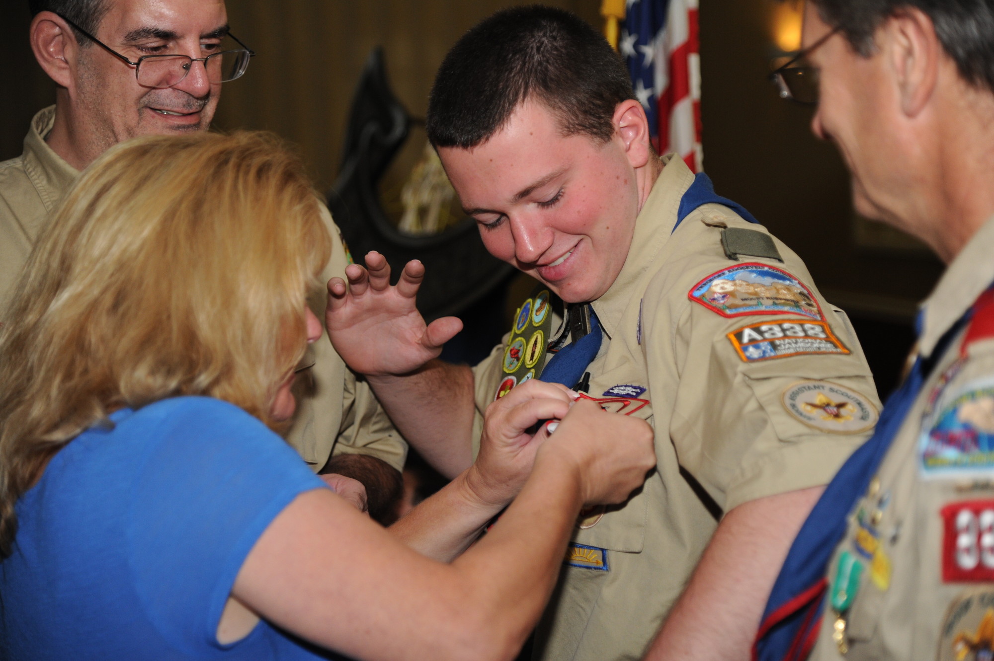 Alex Burns gets his eagle pinned on his shirt by his mom Marybeth while dad Robert watches
