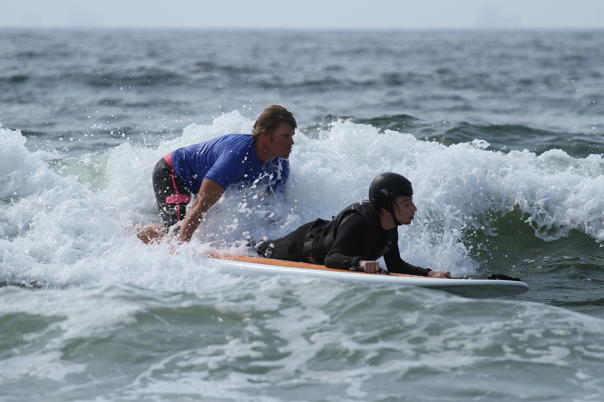 Cliff Skudin of Surf For All situates himself on the back of the board when he paddles into the water with Dylan Hronec, an adaptive surfer from Bellmore, eventually sending him into the waves alone.