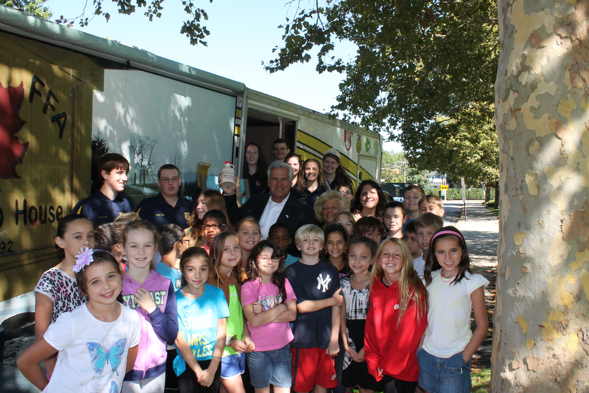 State Senator Dean Skelos, center, Watson School Principal Joan Waldman and the fourth grade class of Mrs. SpallinoFord gathered outside the Mobile Maple Exhibit to get a taste of some fresh maple syrup.
