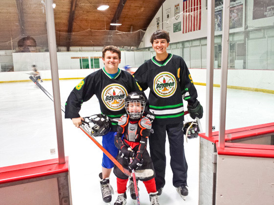 Baymen players Billy Robbins, left, and John Bush joined young skater Evan Dinin last week at the Newbridge Ice Arena, the home rink for the Wantagh-Seaford team.