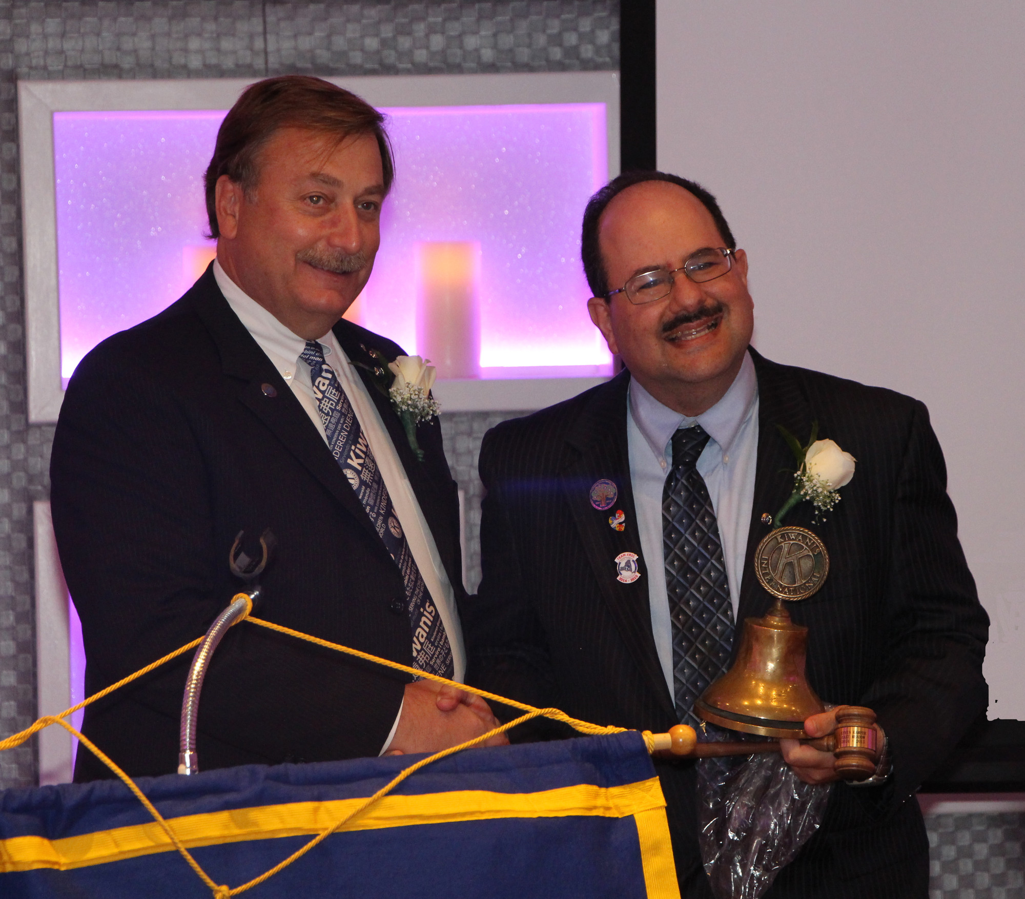 James Smith, left, the outgoing Kiwanis president, gave words of encouragement to new president Kevin Kamper, before handing him his official Kiwanis bell and hammer.