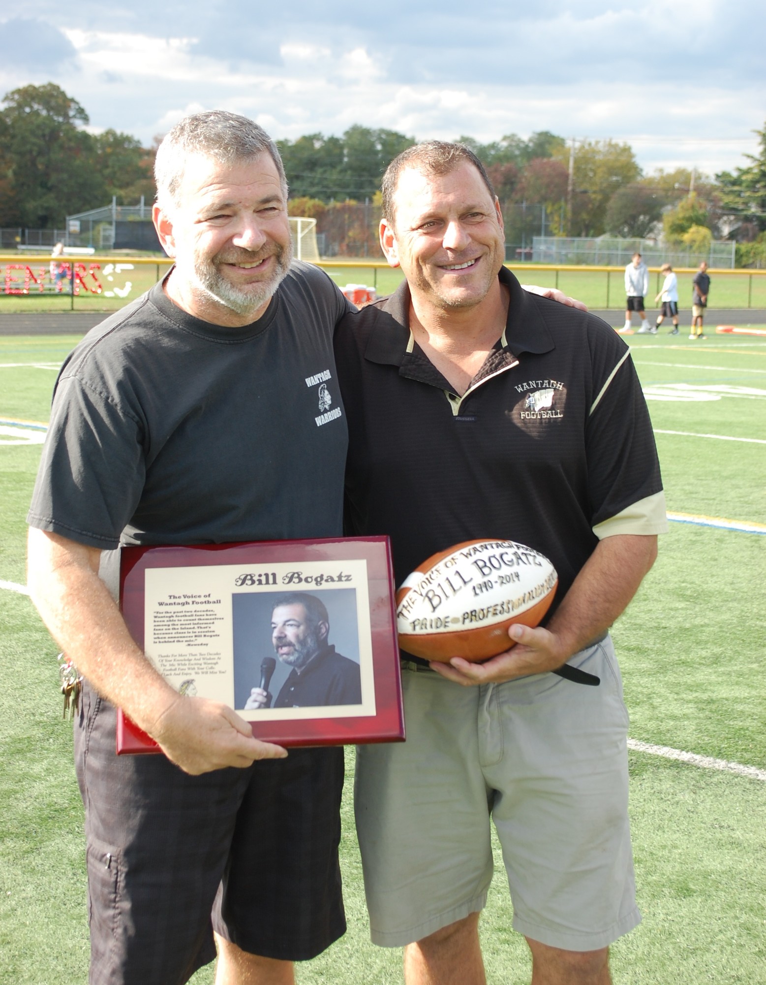 Bill Bogatz, left, who has announced games for 25 seasons, was presented with a football by varsity football coach Keith Sachs.