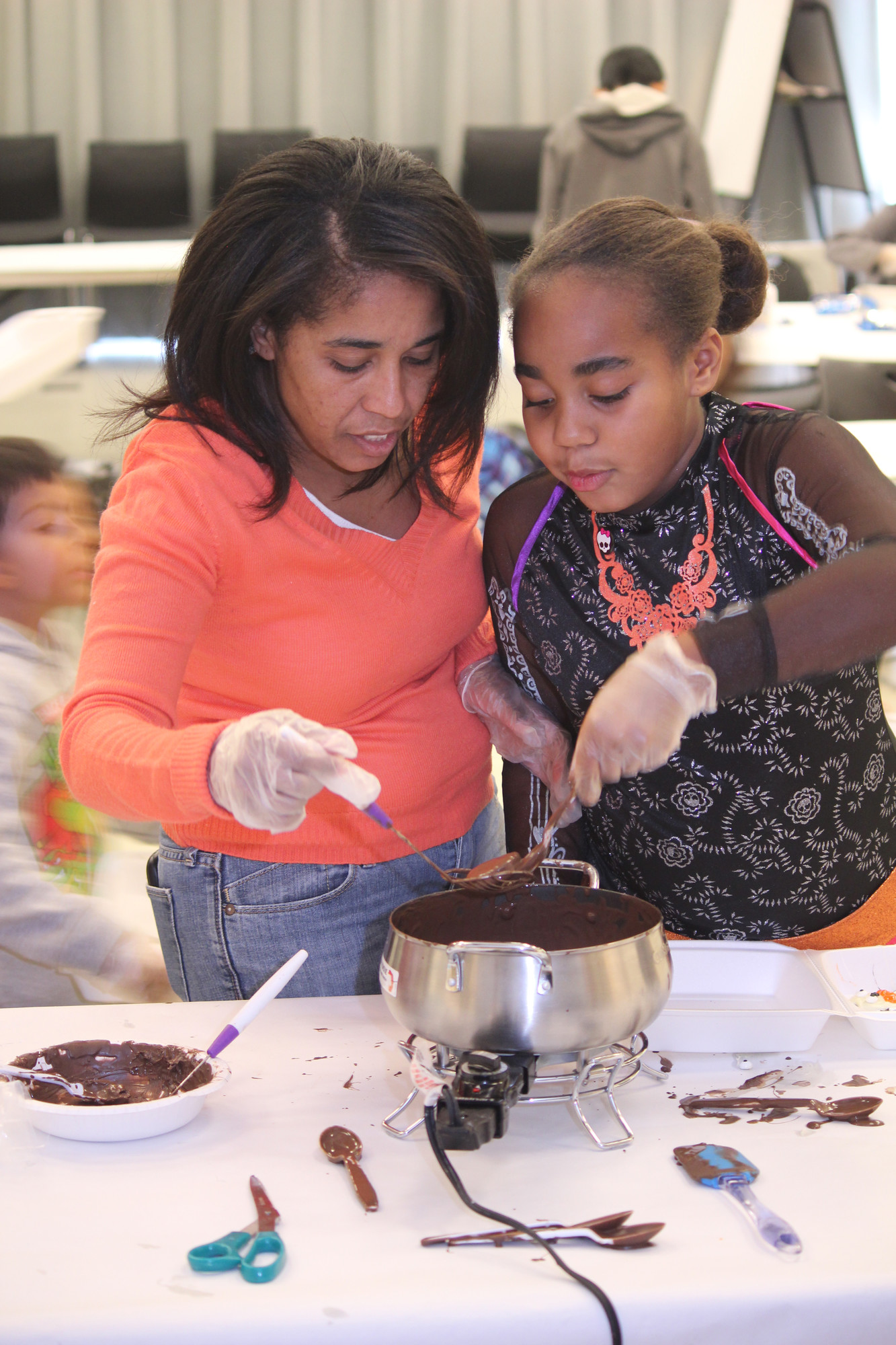 Kilsi Lucas helped her daughter, Gabriela, 8, fish an oreo out of a vat of melted chocolate at Baldwin Public Library.