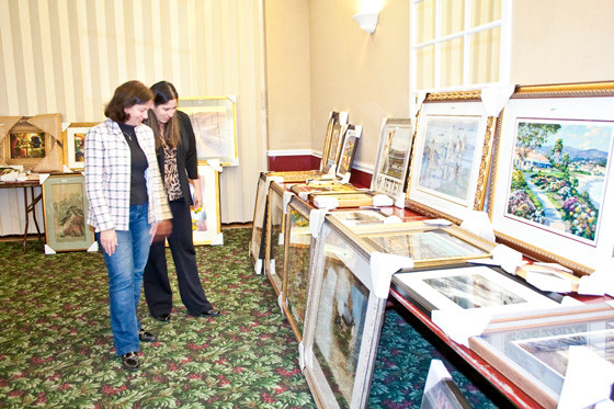 Denise Rogers, president of the Lynbrook Chamber, right, looks at the various artworks up for auction with Dr. Melissa Burak, superintendent of Lynbrook Schools, far left.