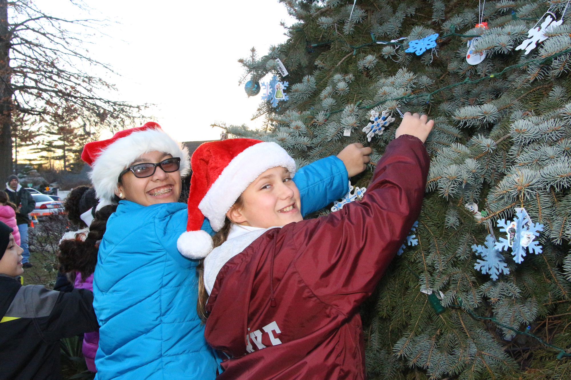 Nyla Batista and Isabella Michaelis, both 12, hung ornaments at the Community Association of Stewart Avenue’s annual holiday lighting in Salisbury last week.