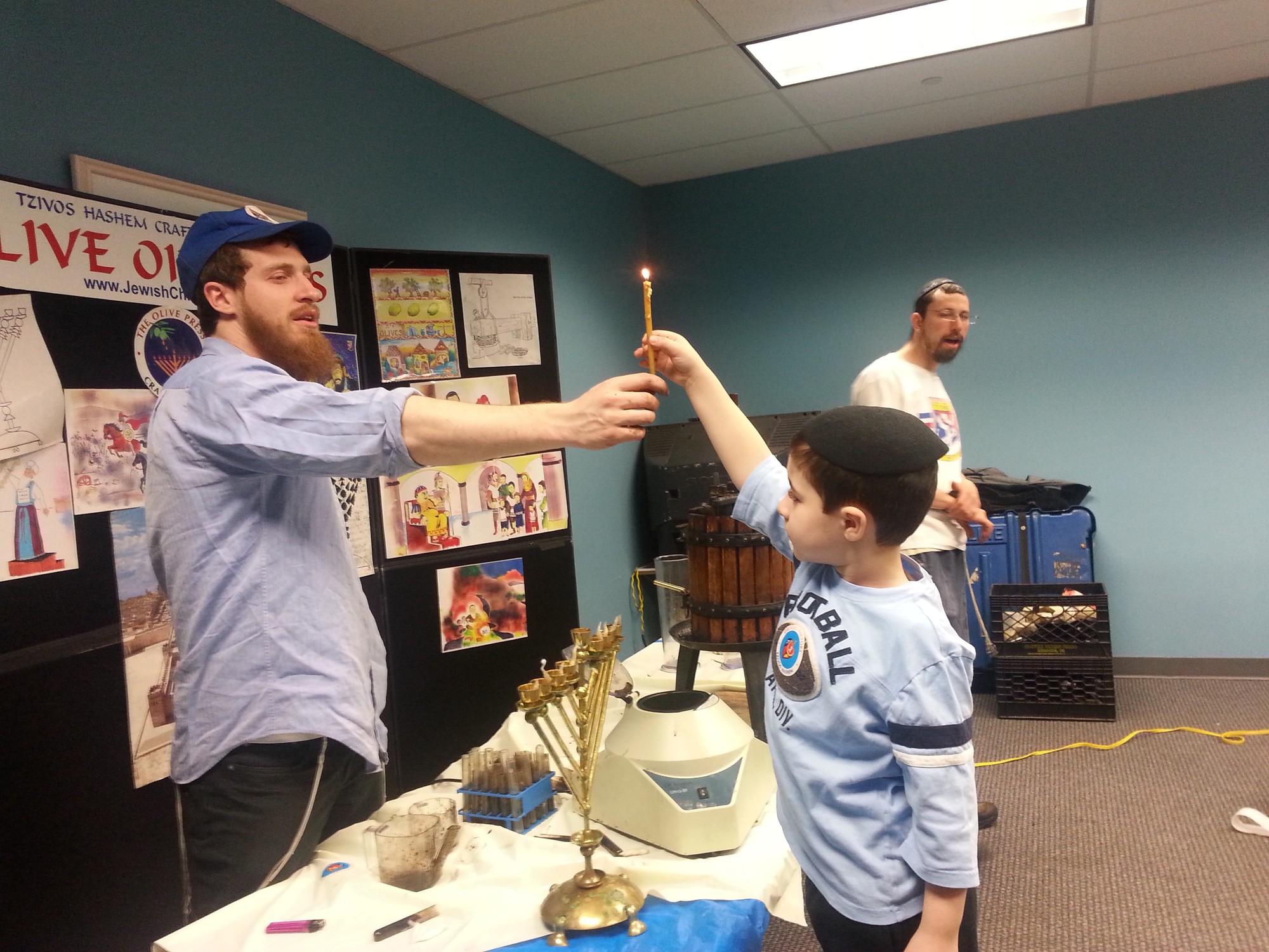 SULAM student Ethan Russo lighting the menorah with olive oil.