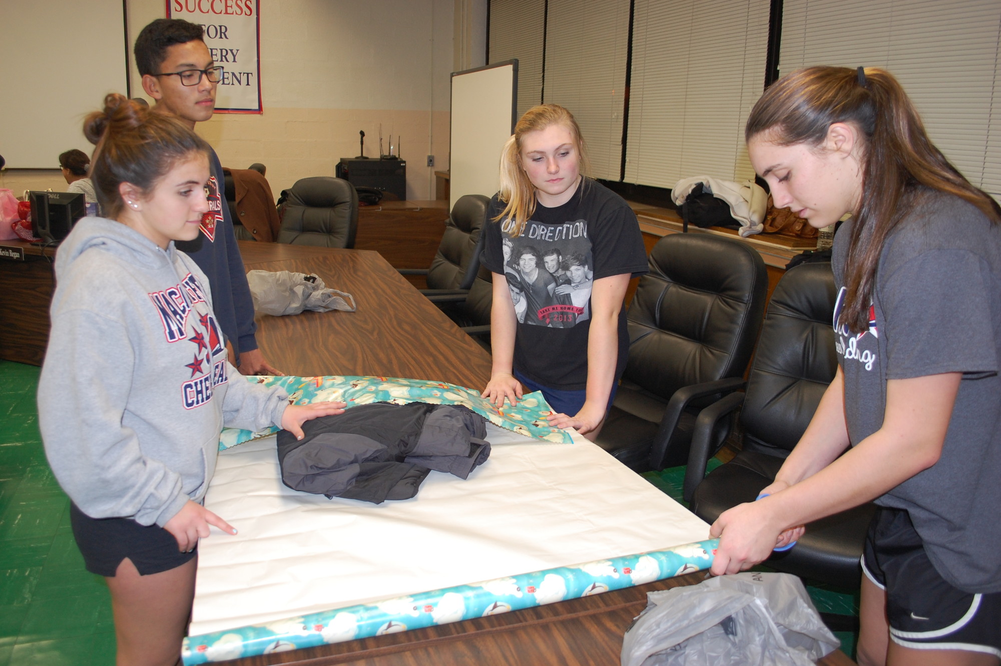MacArthur High School cheerleaders, from left, Jacqueline Langellotti, Elias Martinez, Stephanie Schwartz and Danielle Zangrillo wrapped a winter coat for a local needy child on Dec. 16 at the Levittown Memorial Education Center.