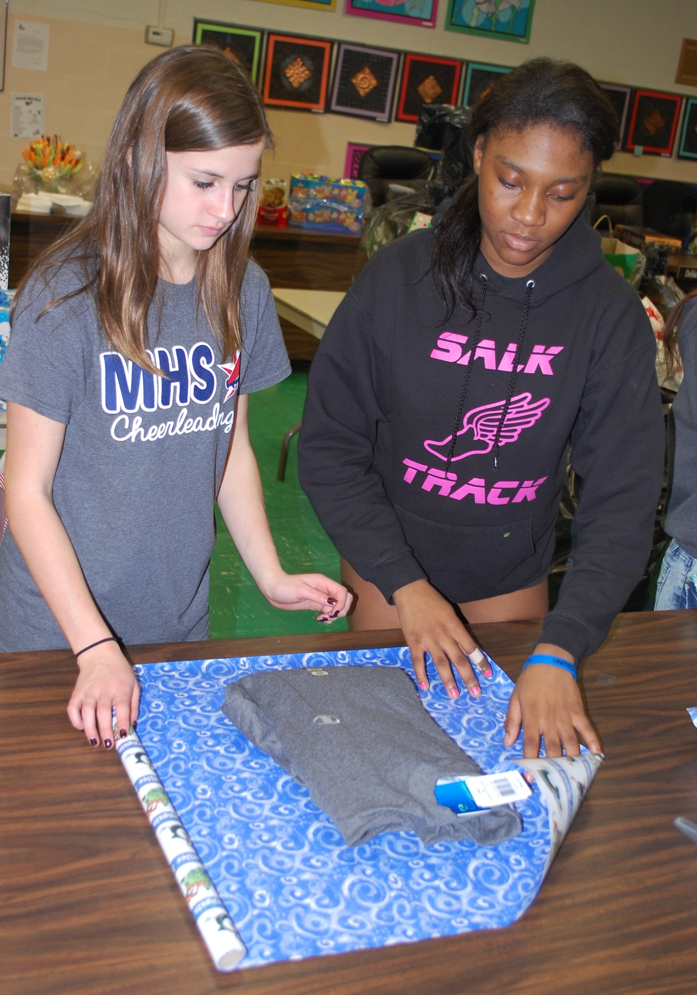 Cheerleaders Cassandra Dolan and Emi Beauliere, both ninth-graders, helped wrap gifts.