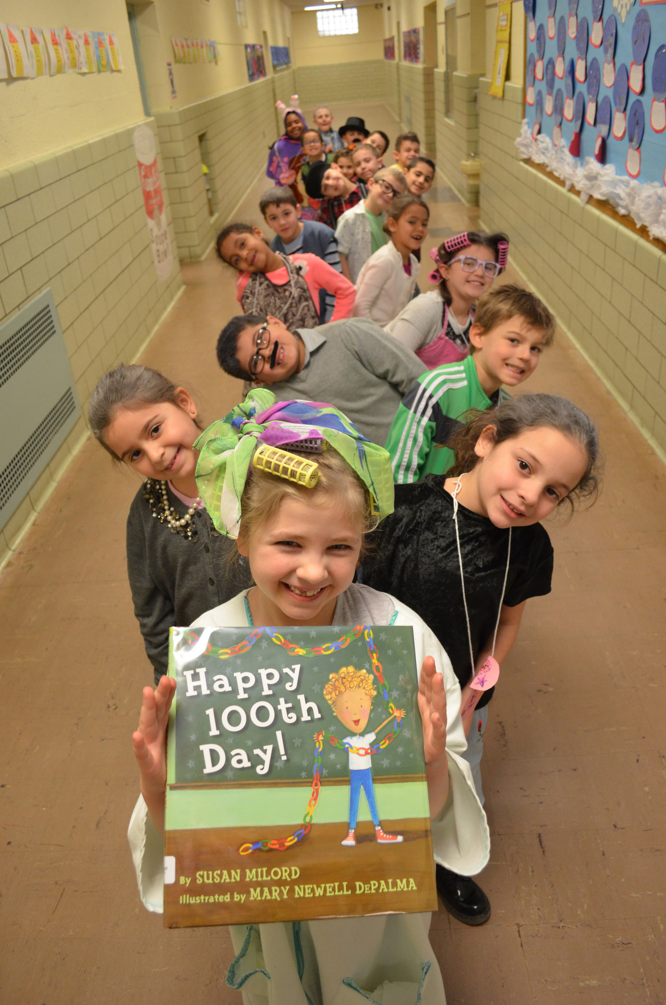 Makaila Schaefer, 7, of Mrs. Salvator’s first grade class posed with the “Happy 100th Day” book.