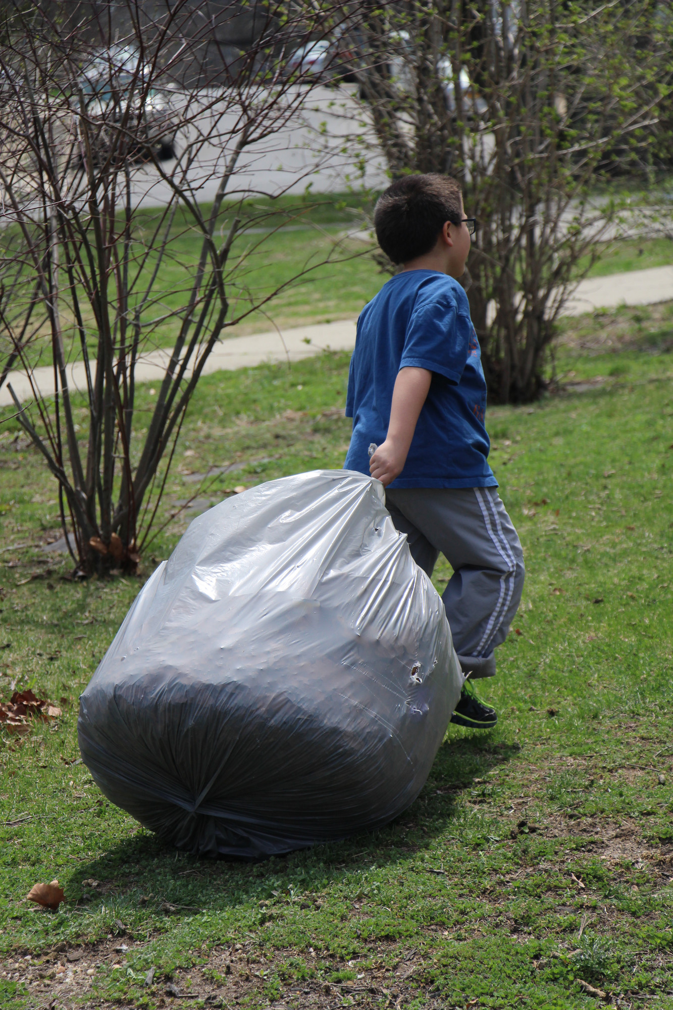 Stelios Potamonsis, 7, carried away a big bag of leaves at Lofts Pond Park last Saturday during an Earth Day Cleanup.