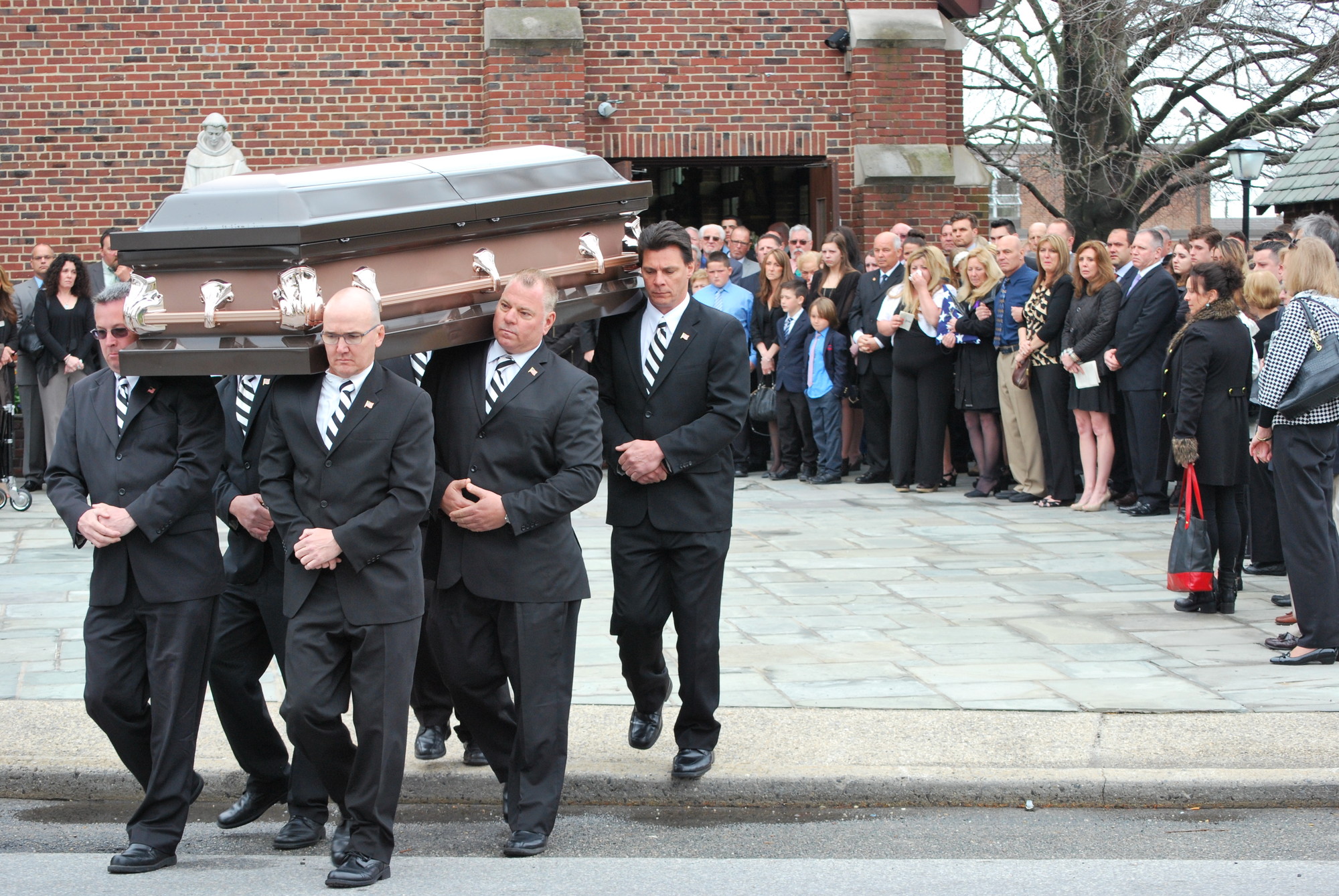 Pallbearers Carried Dan Farrell while family and friends look on.