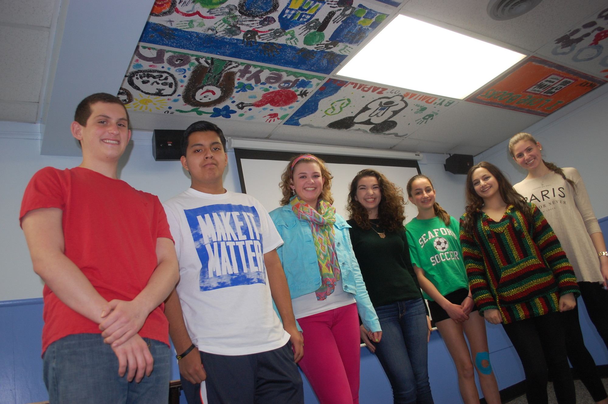 Nearly 100 painted ceiling tiles hang in the Seaford Library’s lower level. Among the artists are, from left, Matthew Zabatta, Mike Emmett, Kenna MacLean, Alison Coggins, Kaitlyn Sidoti, Nicole Merendino and Vicky Zaharopoulos.