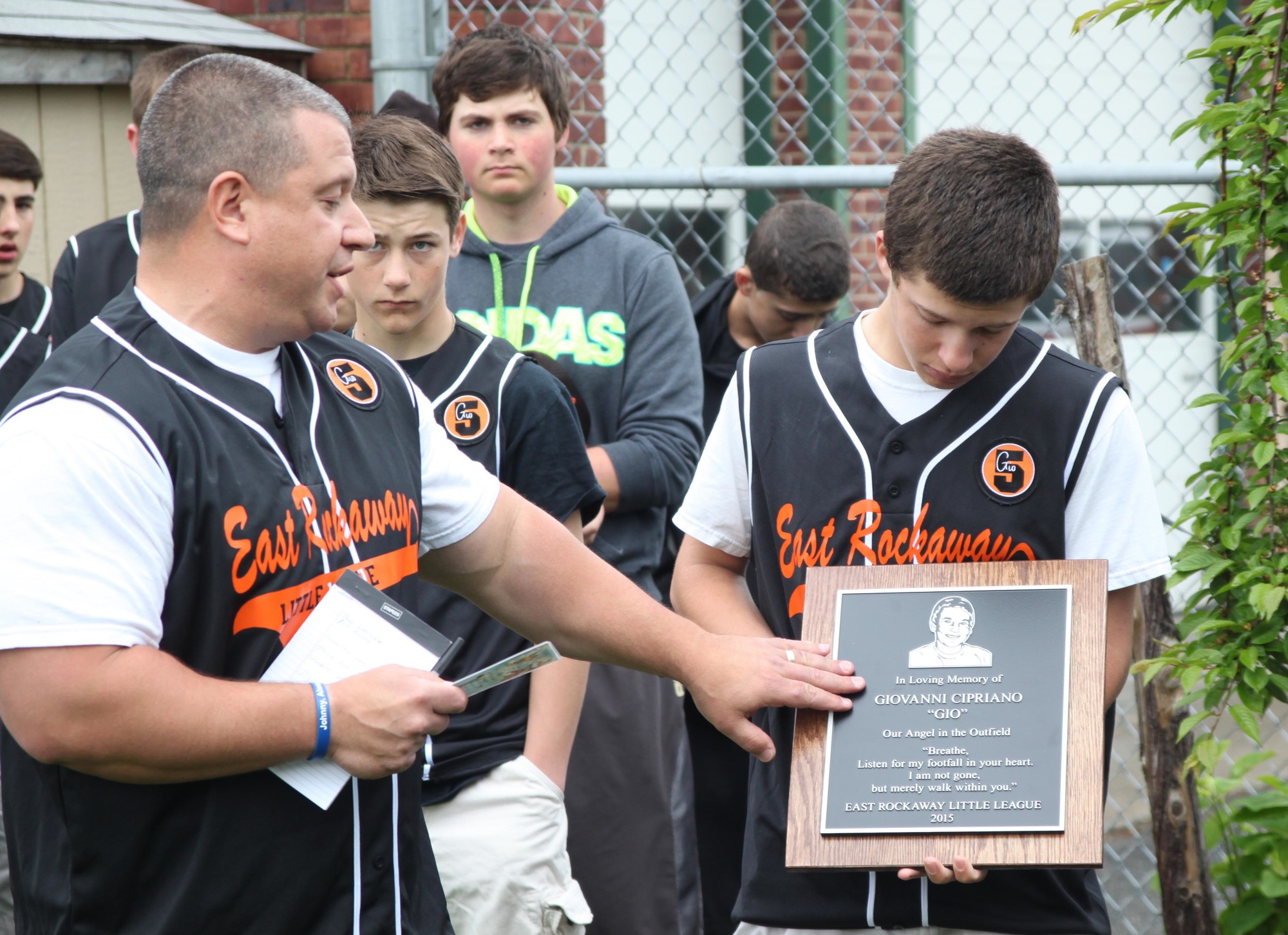 Coach Tom LaBarbera and his son Matthew, one of Gio's teammates, display a plaque in Gio's honor just before presenting it to his family.  The plaque will be mounted on a stone that will sit next to Gio's tree.