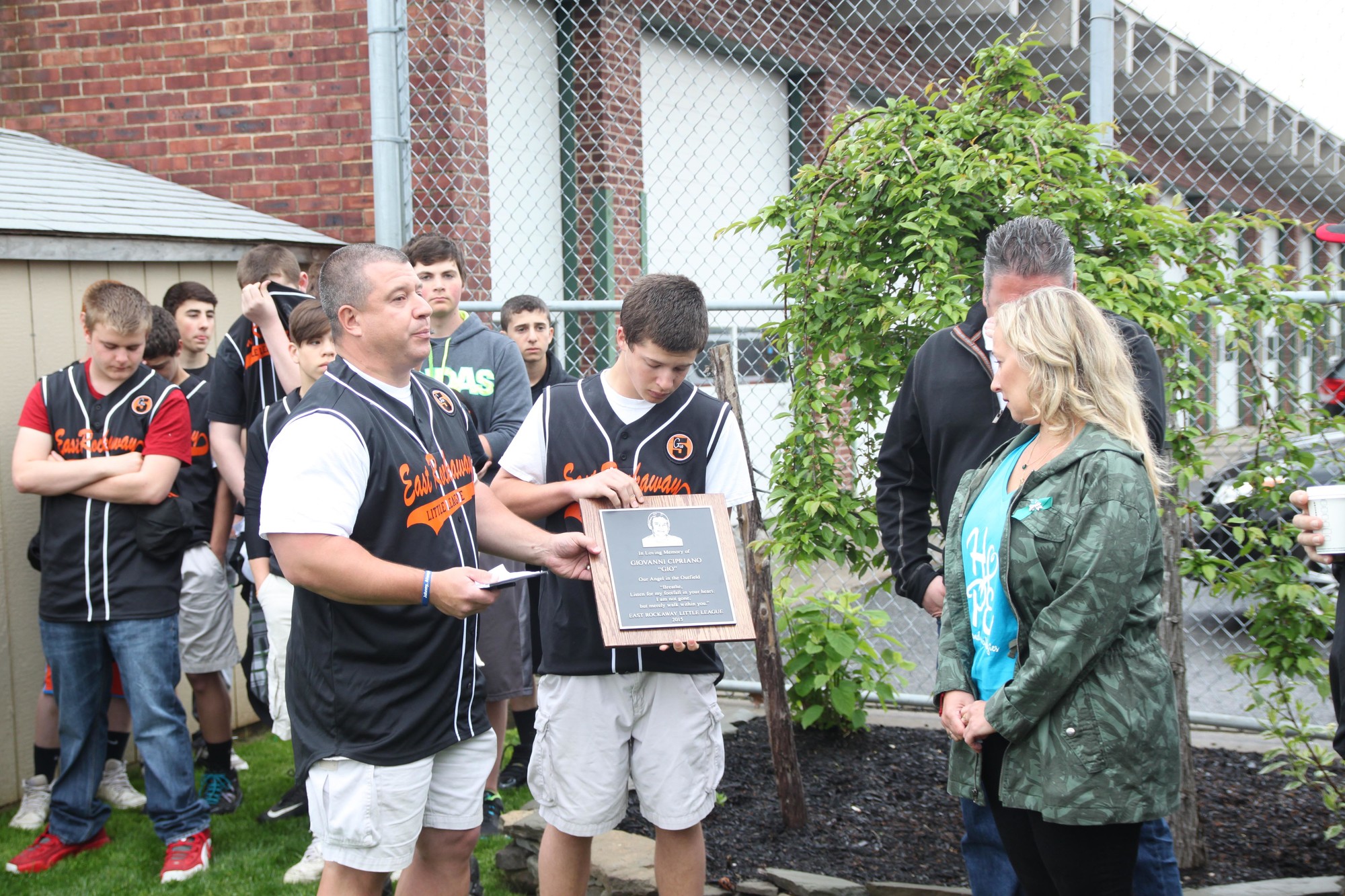 Coach Tom LaBarbera and his son Matthew, one of Gio's teammates, present a plaque in Gio's honor to John and Georgina Cipriano.