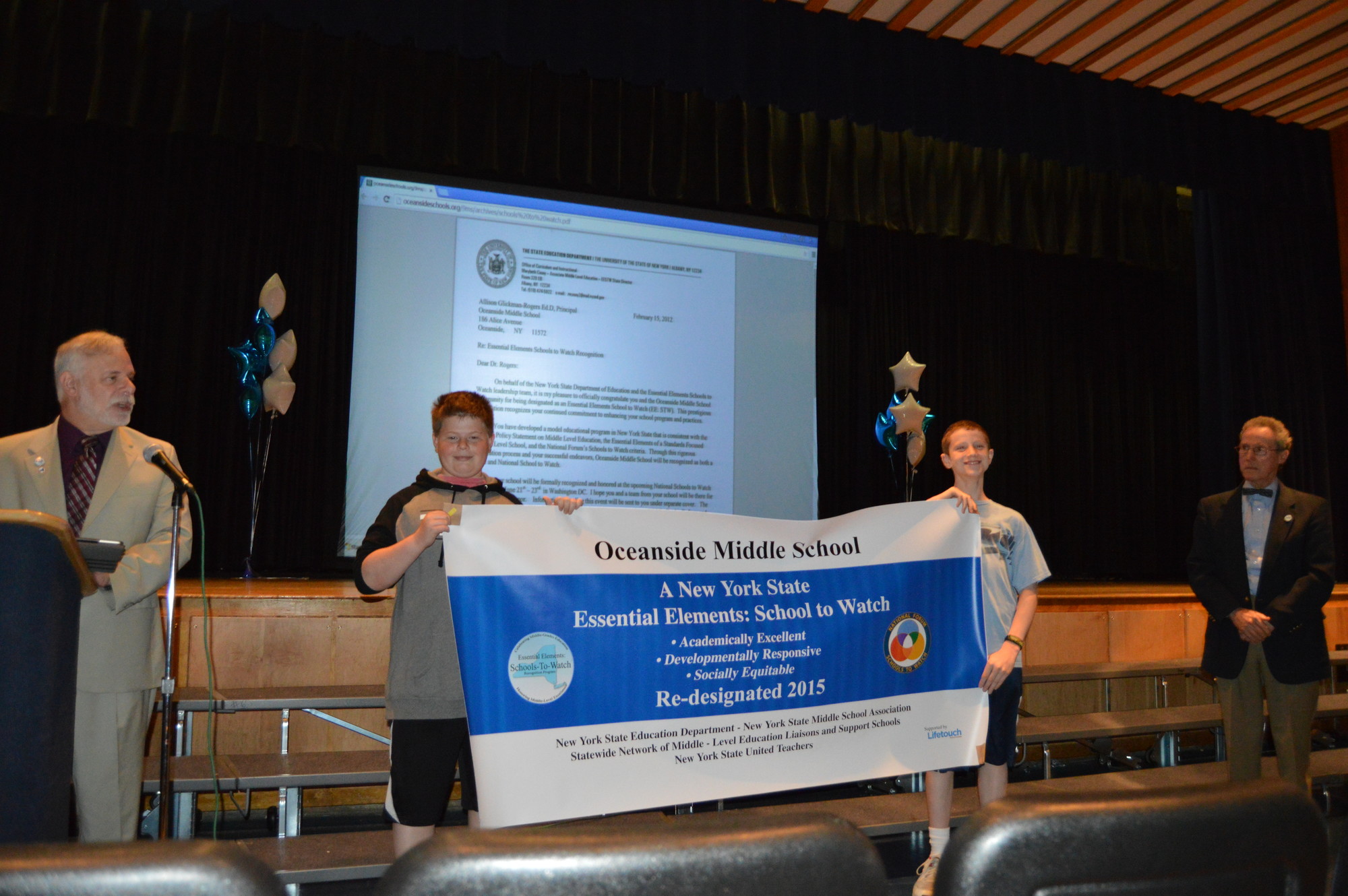 Noah Scott and Paul Lestella held up a banner recognizing Oceanside Middle School as a “School to Watch”.