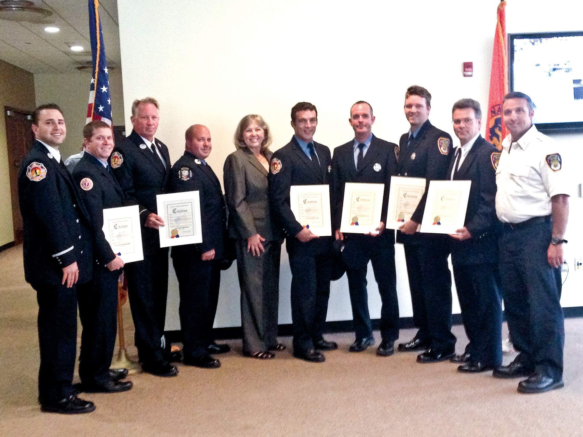 Long Beach firefighters Sam Pinto, far left, Brian Abramson, Brian Pues, John Marino, County Legislator Denise Ford, and firefighters Bryan Jones, Dan Fraser, Chris Koehle, Bill Piazza, and Anthony Fallon at the May 18 ceremony in Mineola.