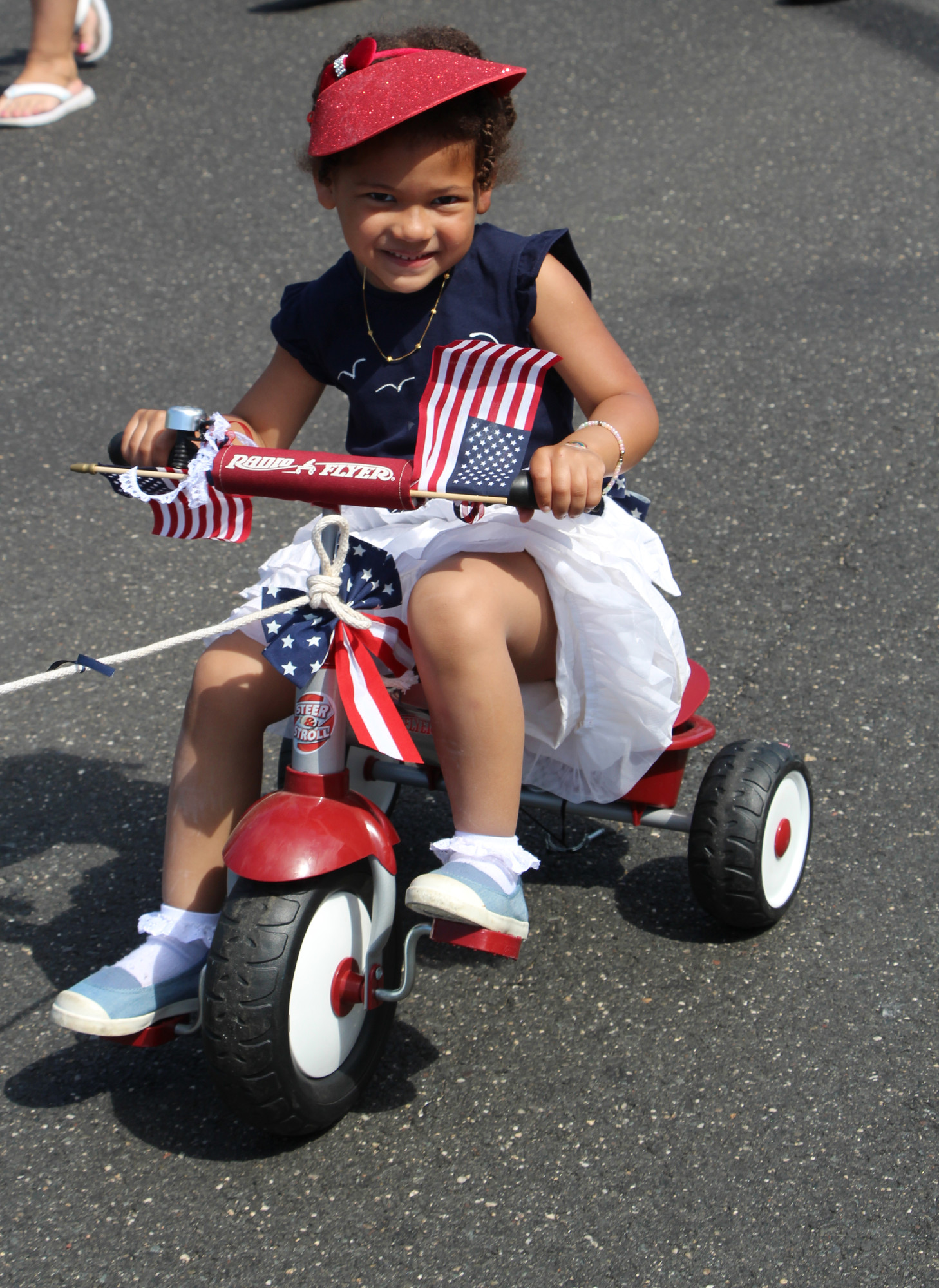 Wearing her red, white and blue, Zoe Fray, 4, rode down Grand Avenue in style with Community Nursery School of Baldwin.