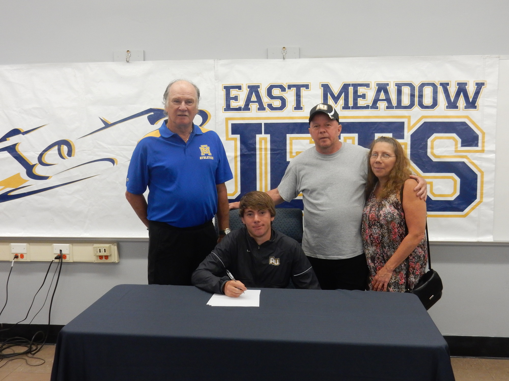 Track star Michael Grady will run at Adelphi University in Garden City. He was with his coach, Jim McGlynn, left, and parents Mike and Judy.