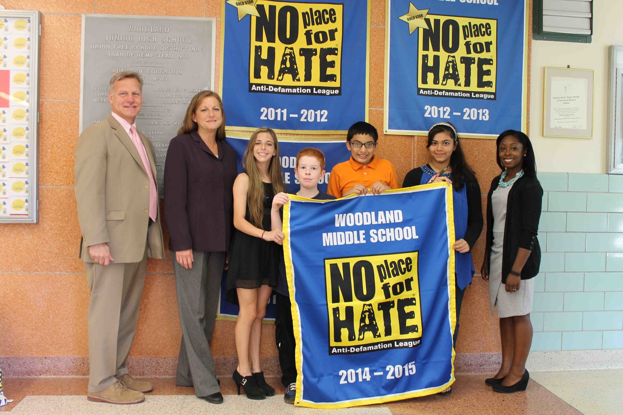 Woodland Middle School Principal James Lethbridge and Assistant Principal Patricia Graham, far left, and Anti-Defamation League representative Amanda Holder, far right, joined Woodland students to display their recently earned “No Place for Hate” banner.