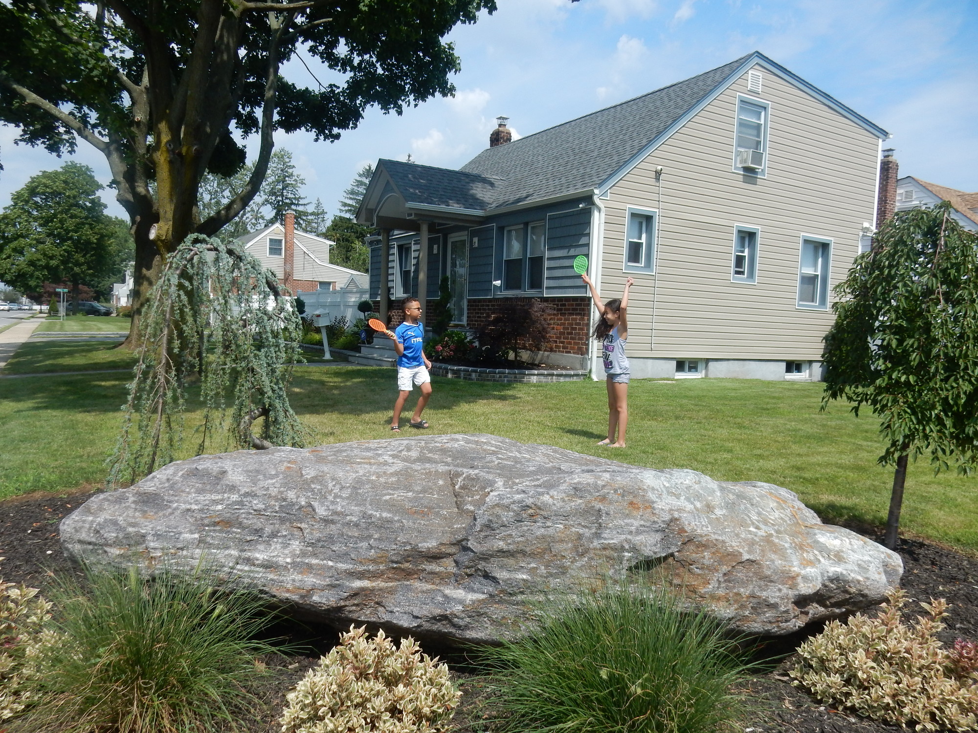 Twins Anthony and Angie Sissons, 9, played behind a 7,000-pound hunk of granite that their parents added to their property, at the corner of Prospect Avenue and Second Street, after a car drove into their home Memorial Day weekend.