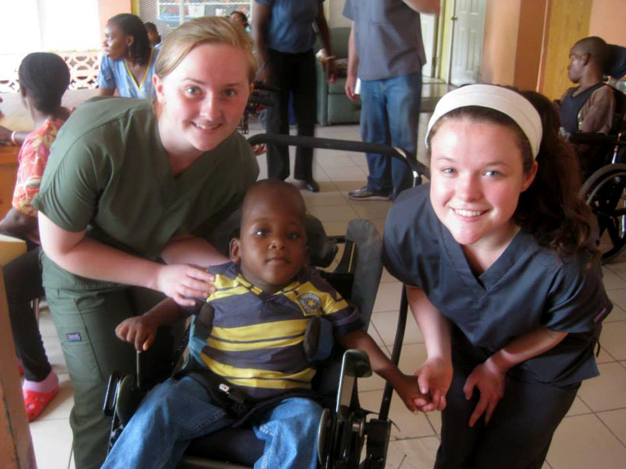Misericordia University students Maria Weidemoyer, Perkiomenville, left, and Kerrie Hall, Lynbrook, New York, assist a child during an occupational therapy service-learning trip to Jamaica.