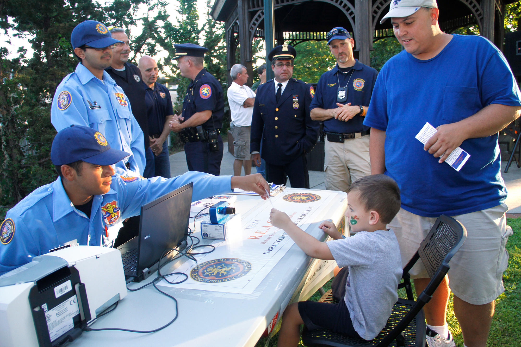 Nassau County Police Explorers were on hand to educate children about safety. Above, George Jaghab handed a Kid Pix ID card to Aiden Lazzarini.