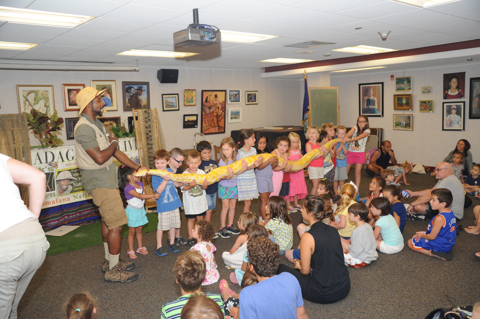 It took 12 brave volunteers to hold the large snake that Erik Callendar brought to the Rockville Centre Public Library.