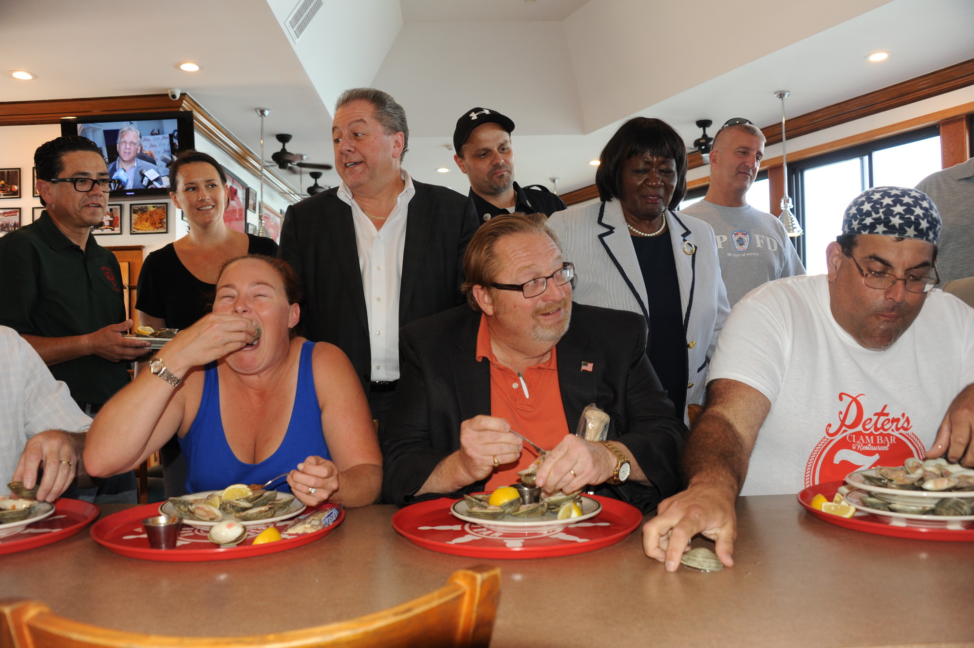 Island Park Mayor Michael McGinty, center, learned the finer points of high-volume clam eating from Ed “Cookie” Jarvis, right, as Peter’s Clam Bar owner Butch Yamali, standing at left, and Hempstead Town Councilwoman Dorothy Goosby, second from right, watched. Jarvis ate 36 clams in 60 seconds. (Penny Frondelli/Herald)