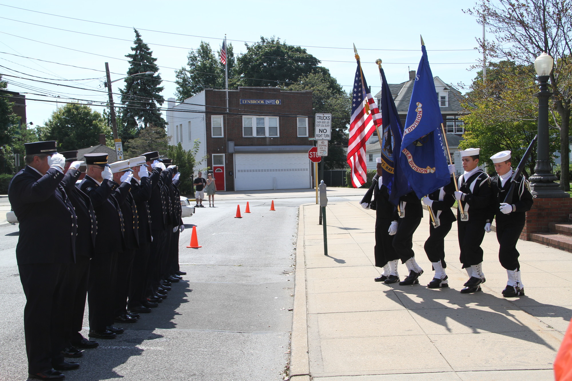 Lynbrook firefighters,   pmembers of Tally-Ho Engine 3, pictured at left, saluted the color guard, represented by the US Naval Sea Cadets.