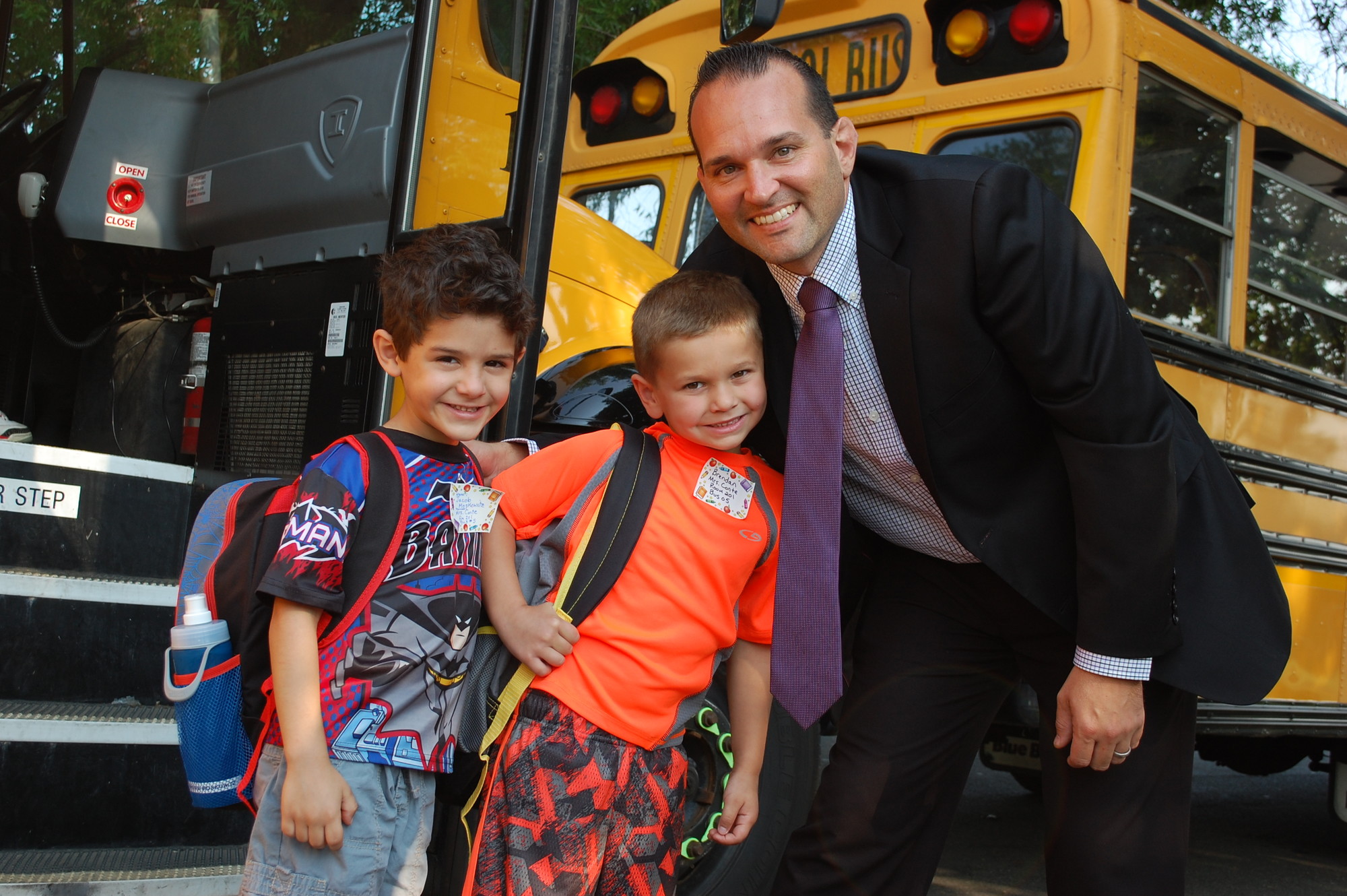 Forest Lake Elementary School Principal Anthony Ciuffo greeted kindergartners and neighbors Jacob Moskowitz, left, and Brenden Wood as they arrived by bus for their first day of school on Sept. 1.