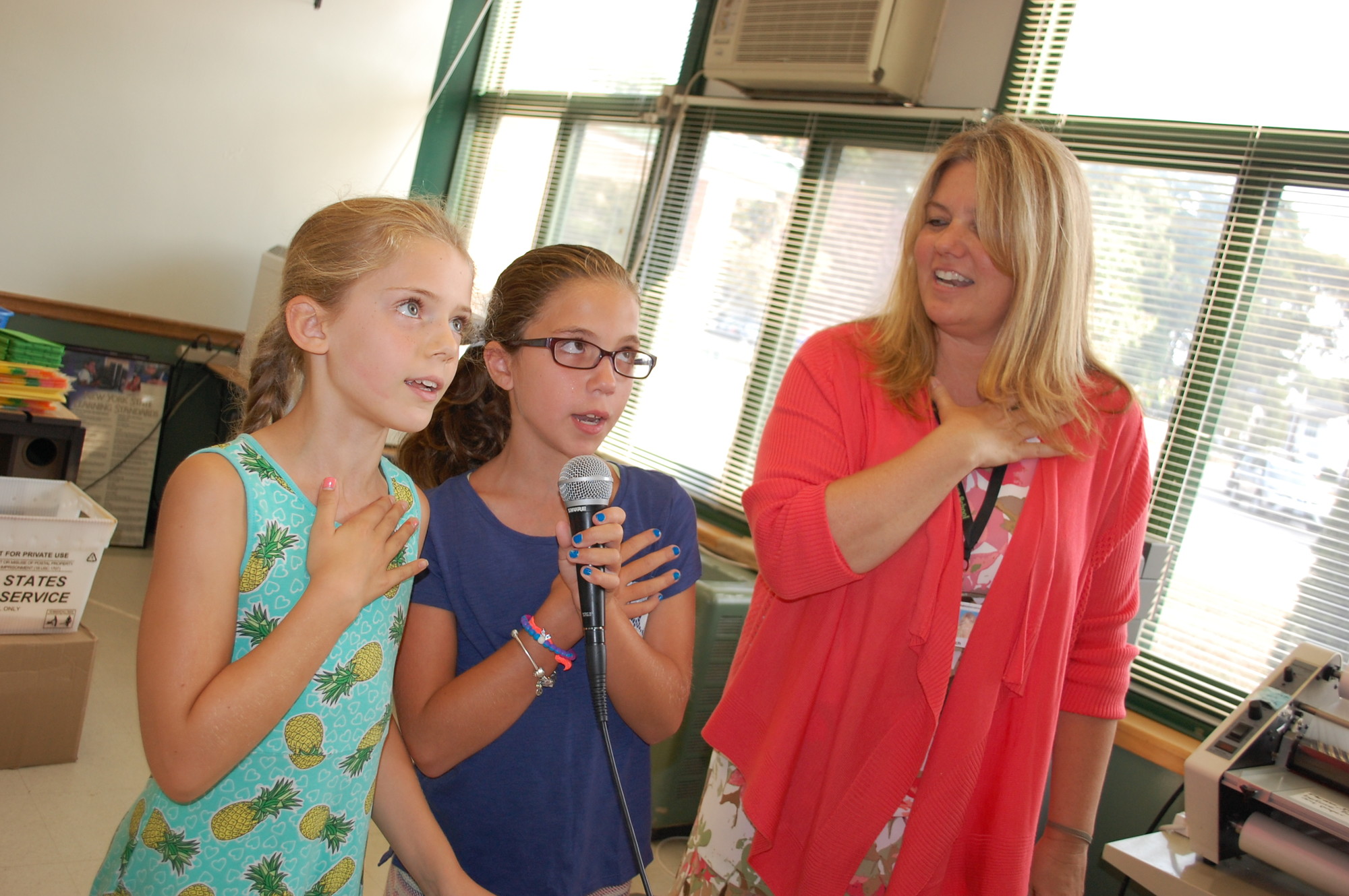 Fifth-graders Emily Bowles, left, and Abby Bussani, along with Principal Debra Emmerich, led the school in the first Pledge of Allegiance of the new year.