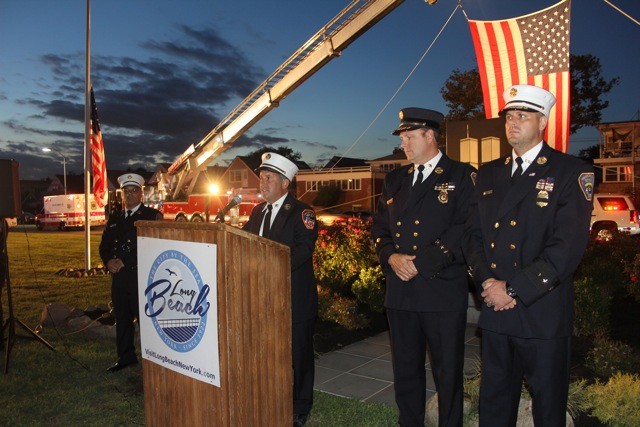 FDNY Chief Larry Spalter reads the names of barrier island residents who perished during the September 11th attacks while, from left, Asst. Chief Rick DiGiacomo, Ex Chief Richard Corbett and Chief of Dept. Robert Tuccillo accompany him at the podium.