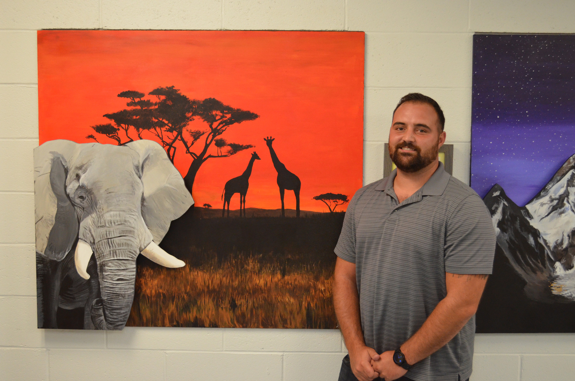 Artist Jonathan Bartlett next to one of the many works of art that he created for the school’s new wing.